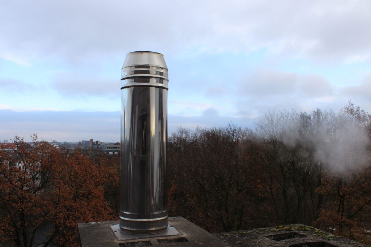 Ein Schornstein vor Bäumen und Himmel