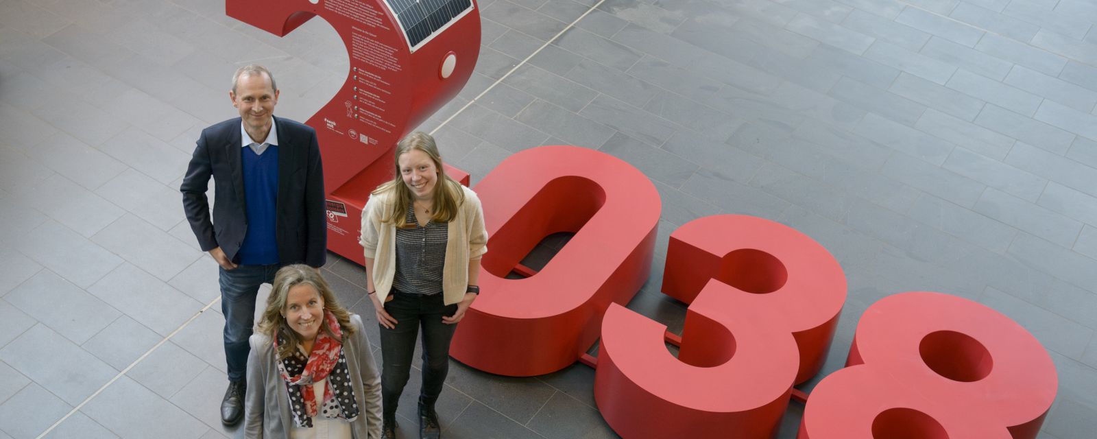 eine menschengroße Zahl 2038 und drei Personen im Vordergrund