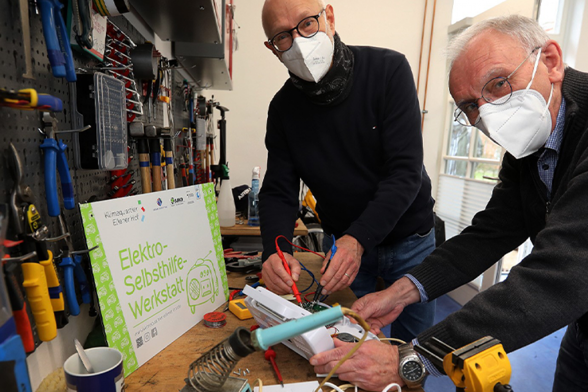 Zwei Männer im Repaircafe, die Elektrogeräte reparieren